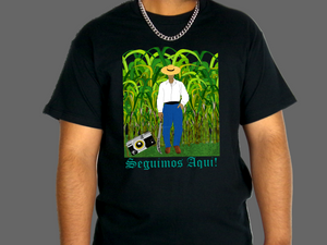 Black t-shirt with a graphic of a person in a cornfield and 'Seguimos Aqui!' text.